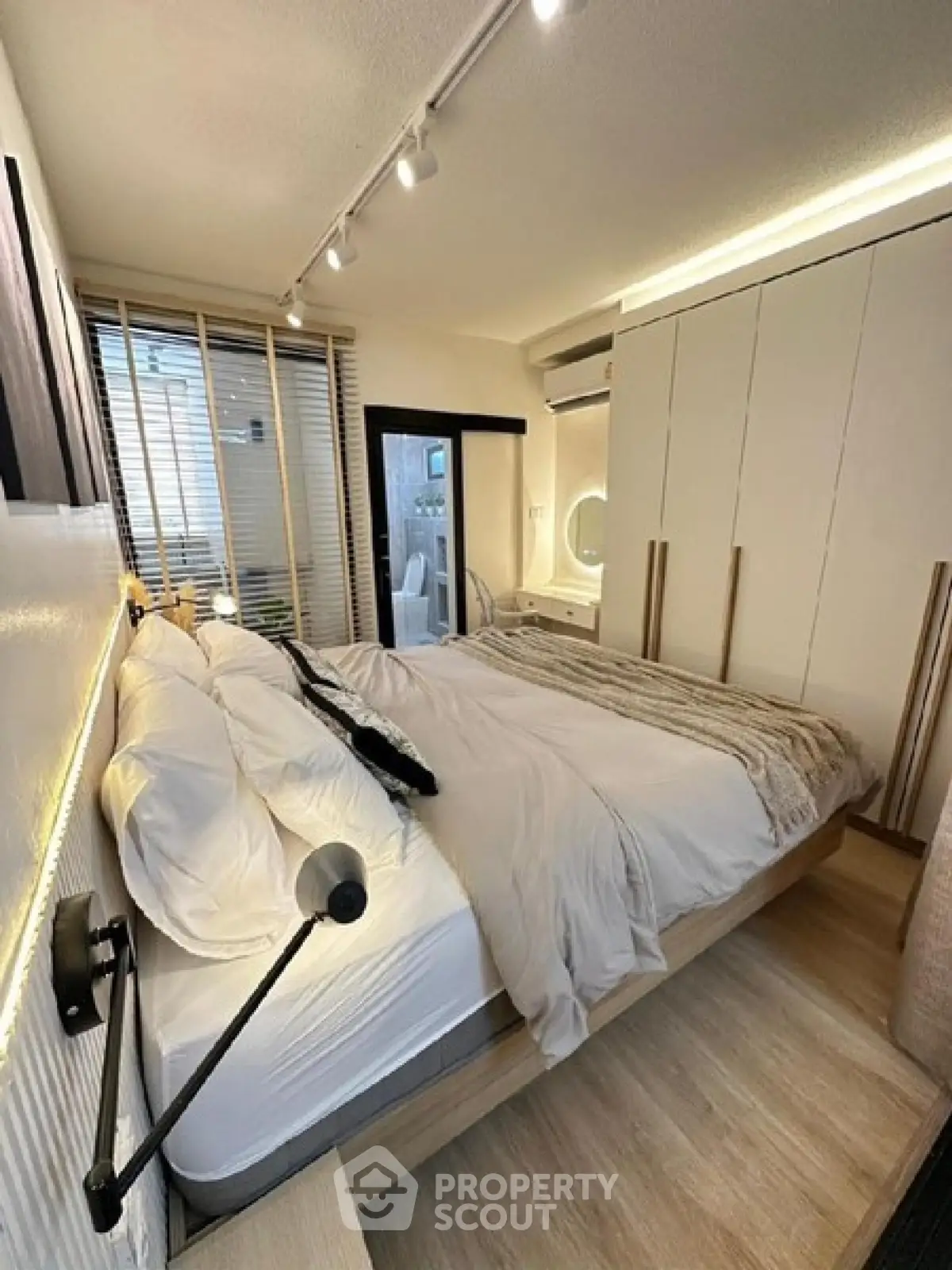 Modern bedroom with stylish lighting and large bed in a cozy apartment setting.