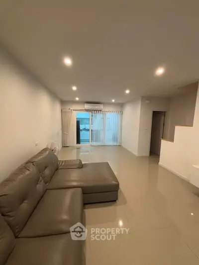 Spacious modern living room with sleek sofa and large windows for natural light.