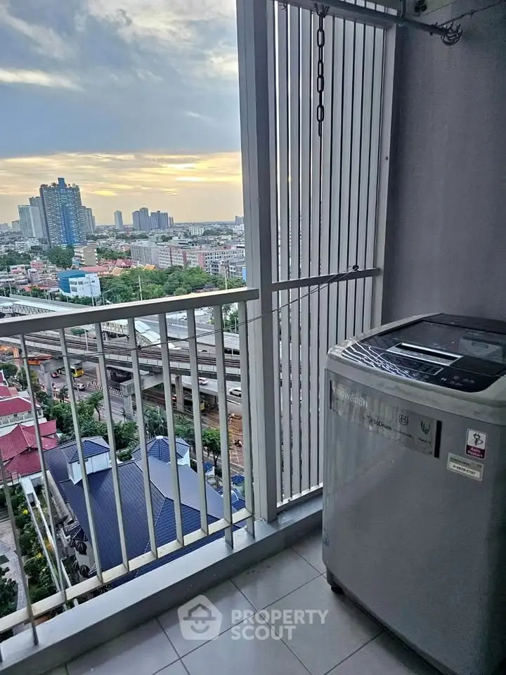 High-rise balcony with washing machine and stunning city view at sunset.
