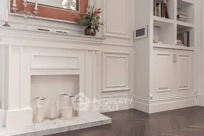 Elegant living room with classic white fireplace and built-in shelves, featuring sophisticated decor.