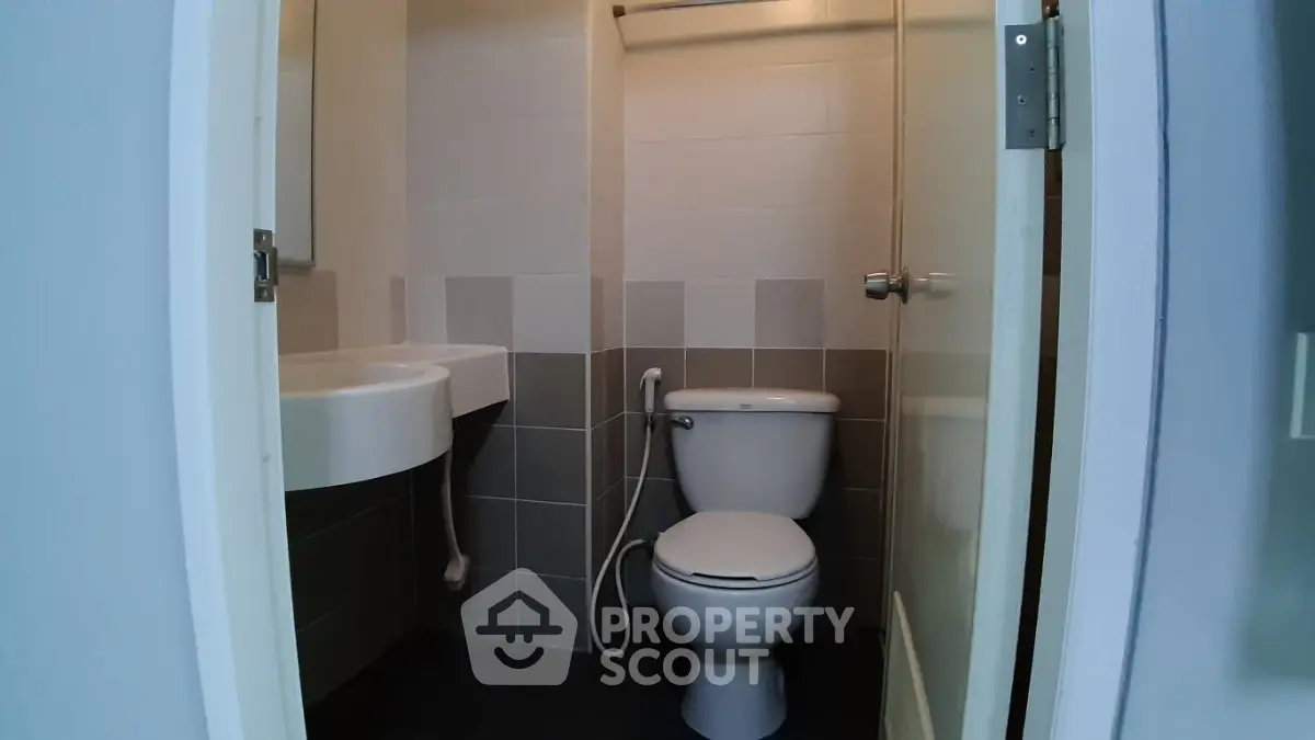 Compact bathroom with modern fixtures and neutral tiles, featuring a toilet and sink.