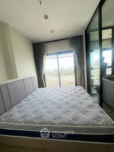 Spacious bedroom with large window and balcony access, offering abundant natural light and city views.
