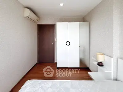 Modern minimalist bedroom with white wardrobe and air conditioning unit.