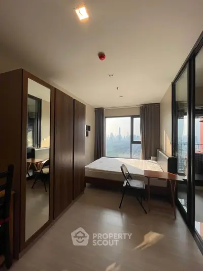 Modern bedroom with city view, large window, and stylish furniture in a high-rise apartment.