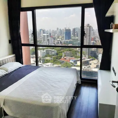 Modern bedroom with stunning city view from large window in high-rise apartment.