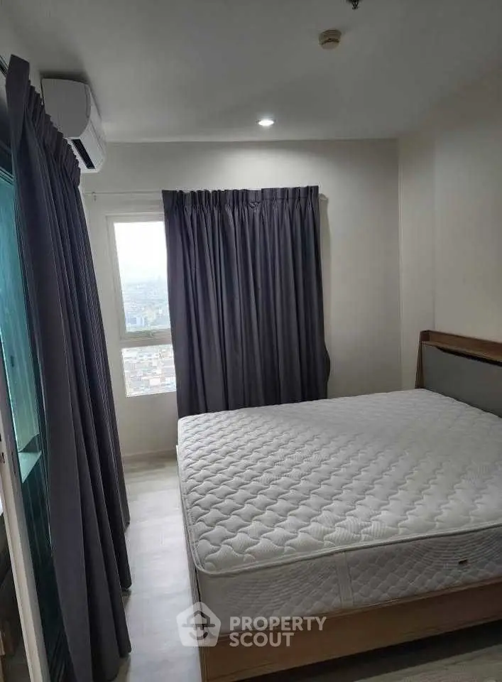 Cozy bedroom with large window and modern furnishings in a high-rise apartment.