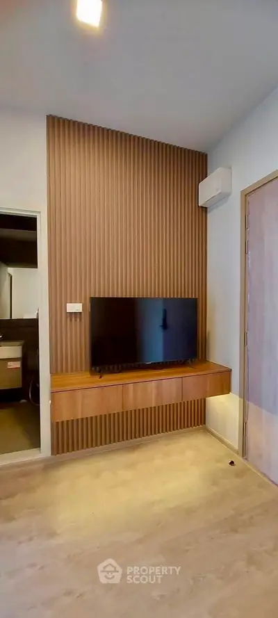 Modern living room with wooden accent wall and mounted TV, featuring sleek design and warm lighting.