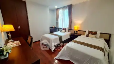Elegant twin bedroom with wooden flooring and stylish decor, perfect for a cozy and comfortable stay.