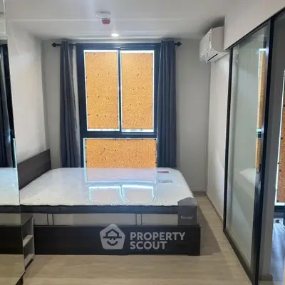 Modern bedroom with large window and sleek furnishings in urban apartment.