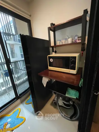 Compact kitchen corner with microwave and fridge, overlooking balcony view.