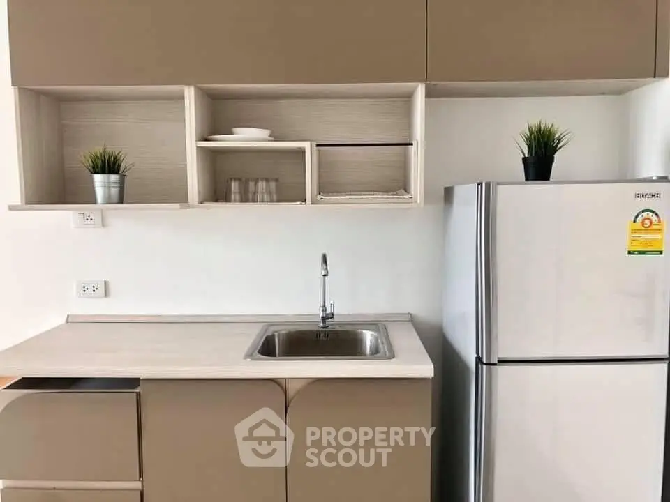 Modern kitchen with sleek cabinetry and stainless steel fridge in a compact layout.