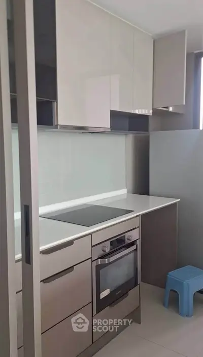Modern kitchen with sleek cabinetry and built-in oven, featuring a compact and efficient design.