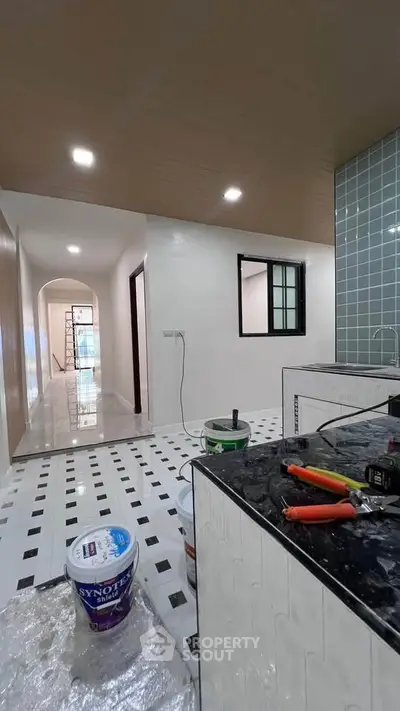 Modern kitchen under renovation with sleek black countertops and tiled backsplash.