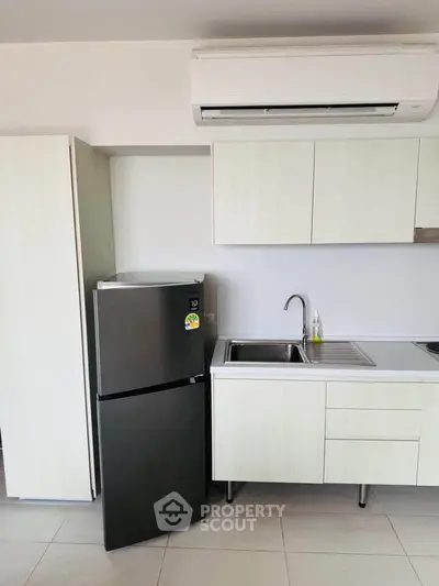 Modern kitchen with sleek cabinetry and stainless steel fridge in a contemporary apartment.