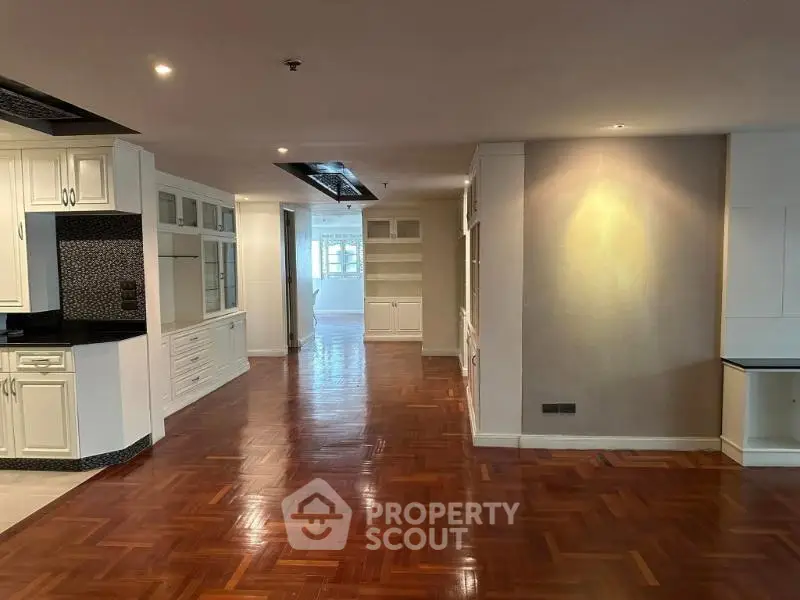 Spacious open-plan living area with elegant wooden flooring and modern cabinetry.