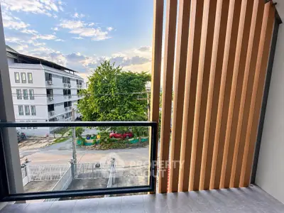 Modern balcony with wooden slats offering a serene view of the neighborhood and lush greenery.