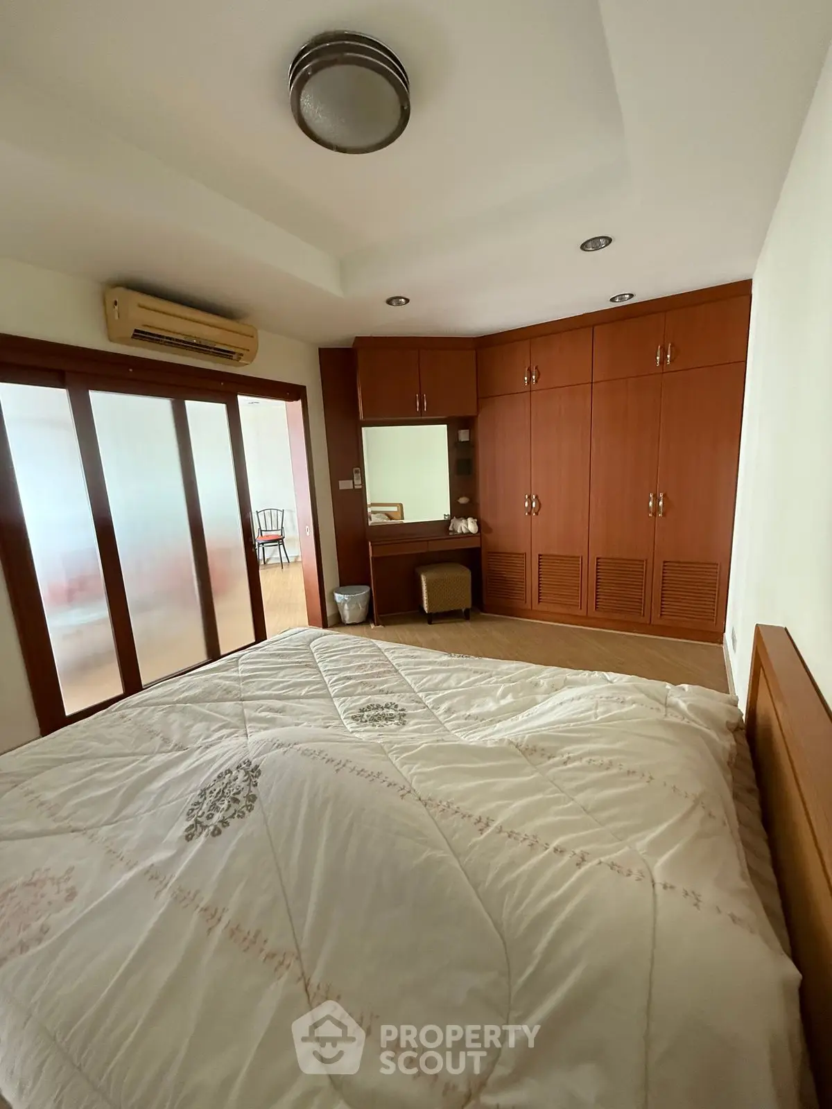 Cozy bedroom with built-in wooden wardrobe and sliding glass doors to balcony.