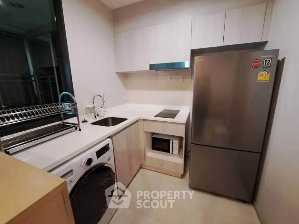 Modern kitchen with sleek appliances and integrated washing machine in compact layout.