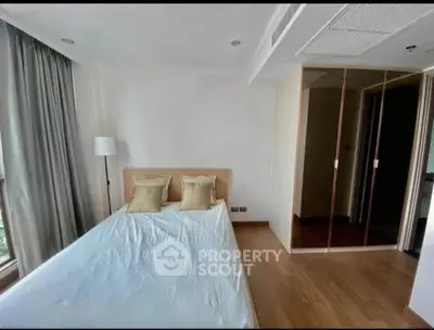 Modern bedroom with wooden flooring and large window for natural light.