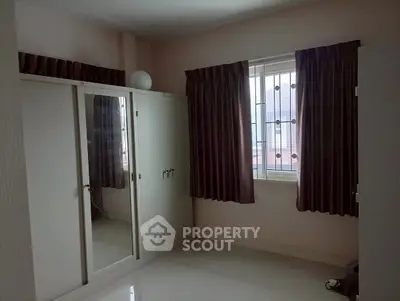 Spacious bedroom with large mirrored wardrobe and window with curtains.