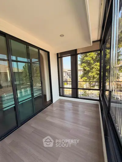 Spacious sunlit balcony with large glass doors and scenic view, perfect for relaxation and enjoying the outdoors.