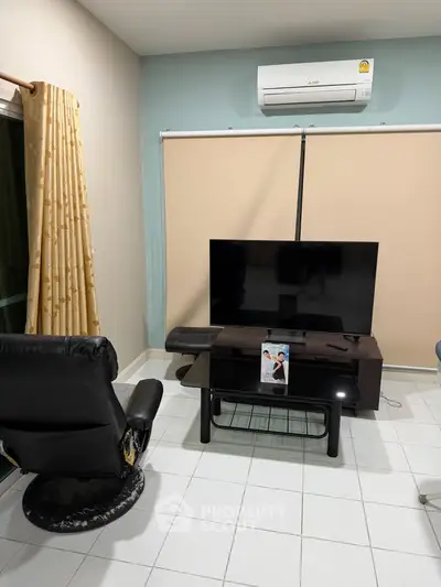 Cozy living room with modern TV setup and air conditioning, perfect for relaxation.