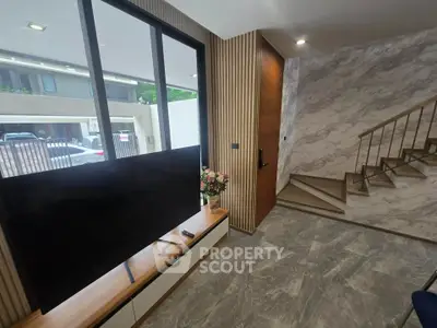 Modern interior with stylish TV setup and elegant staircase in a contemporary home.