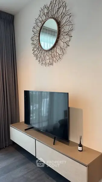 Modern living room with stylish TV setup and decorative mirror.