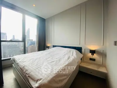 Modern bedroom with city view, featuring large windows and elegant decor.