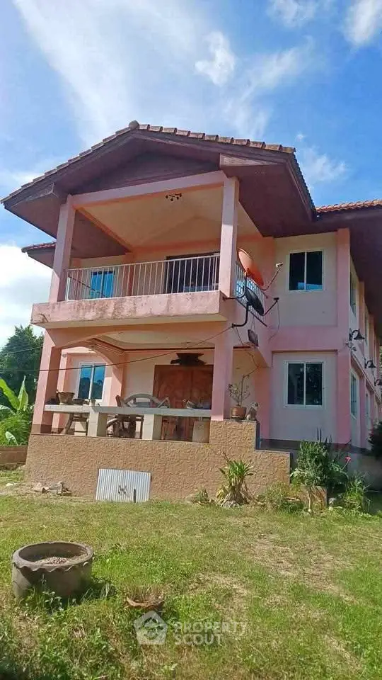 Charming two-story pink house with spacious balcony and lush garden