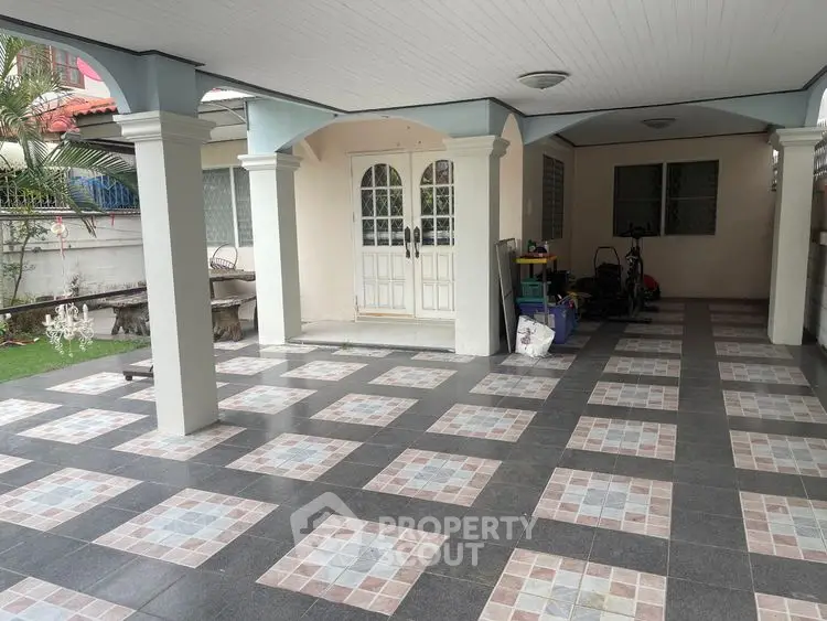 Spacious covered parking area with tiled flooring and garden view.
