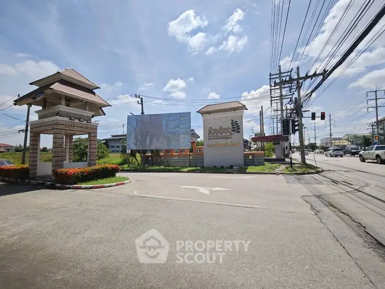 Entrance to a residential community with clear skies and street view.