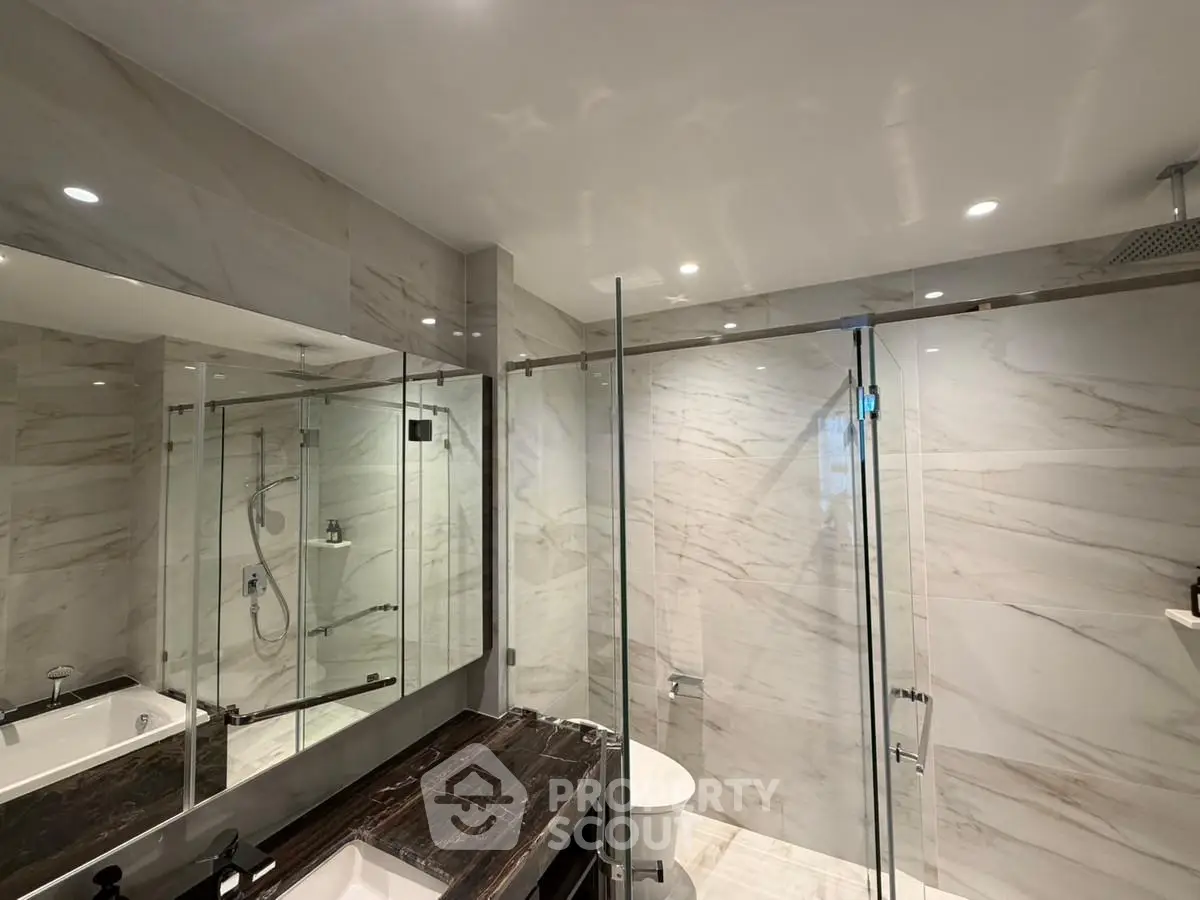 Luxurious modern bathroom with glass shower and marble finishes