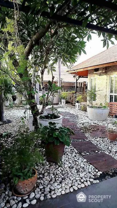 Charming garden with stone pathway and lush greenery in a serene residential setting.