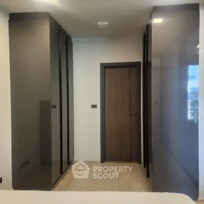 Modern bedroom with sleek dark wardrobes and wooden door