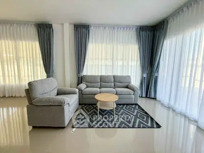 Spacious living room with modern gray sofas and elegant curtains, perfect for relaxation and entertaining.