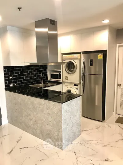 Modern kitchen with sleek appliances and stylish black backsplash in a contemporary apartment.