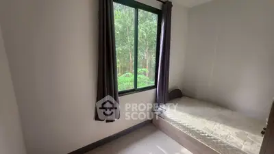 Cozy bedroom with large window and lush green view, perfect for relaxation.