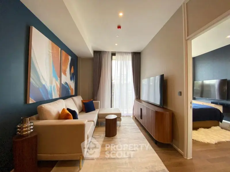 Modern living room with stylish decor and large TV, adjacent to a cozy bedroom.