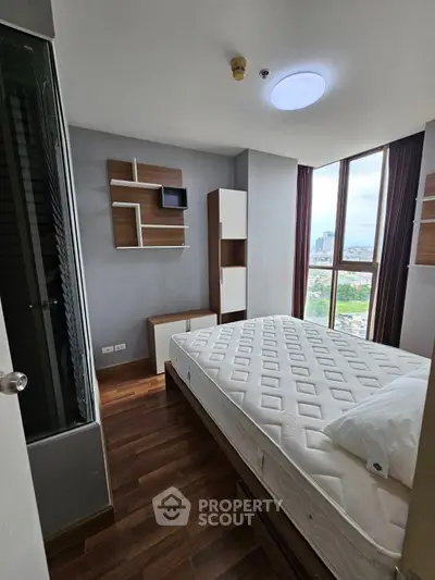 Modern bedroom with city view, featuring stylish shelving and hardwood floors.