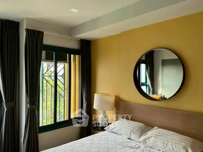 Cozy bedroom with modern decor and large window for natural light.