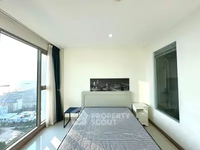 Bright bedroom with large window offering stunning city and sea views, featuring modern decor and minimalistic design.