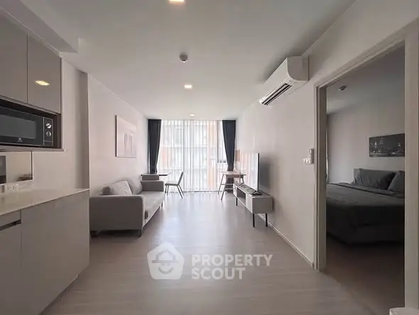 Modern open-plan living room with sleek kitchen and cozy bedroom in a stylish apartment.