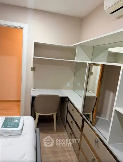 Modern bedroom with built-in desk and storage, featuring sleek design and ample shelving.