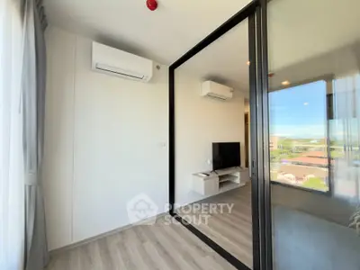 Modern living room with glass partition and air conditioning, featuring sleek flooring and a scenic view.