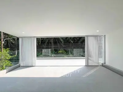 Spacious modern balcony with glass railing and lush garden view, perfect for relaxation and outdoor enjoyment.