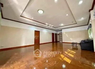 Spacious living room with polished wooden floors and elegant ceiling lights.