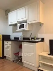 Compact kitchen with white cabinets and microwave in cozy apartment