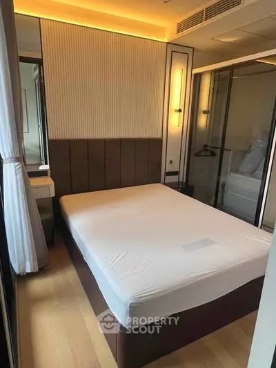 Modern bedroom with stylish lighting and large window, featuring a comfortable bed and sleek design.