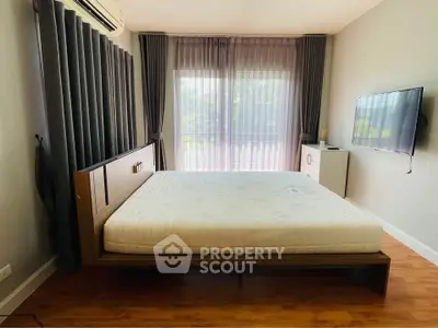 Spacious bedroom with modern decor and large window for natural light.